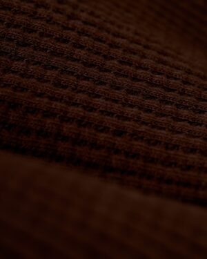 A close-up view of the brown 100% cotton fabric with a waffle weave pattern, reminiscent of the exquisite texture found in Dandy Del Mar's The Cannes Waffle Knit Robe - Carajillo.