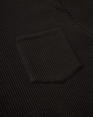 Close-up of The Cannes Waffle Knit Tee - Albatross by Dandy Del Mar, highlighting the dark waffle knit texture and a single pocket with sewing details.
