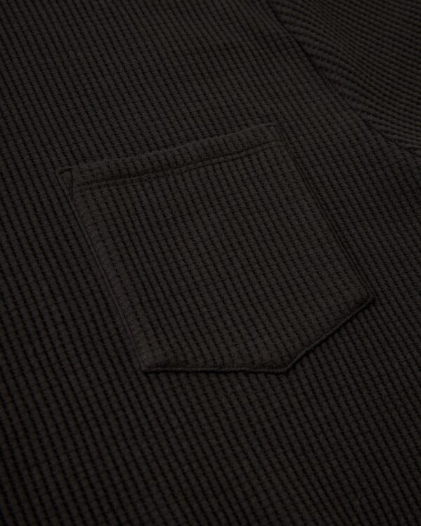 Close-up of The Cannes Waffle Knit Tee - Albatross by Dandy Del Mar, highlighting the dark waffle knit texture and a single pocket with sewing details.