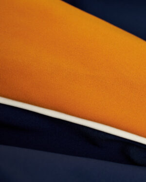 A close up of an European fit Dandy Del Mar Cassis Square Cut Swim Brief - Anchor in vibrant orange and blue fabric for leisure activities.