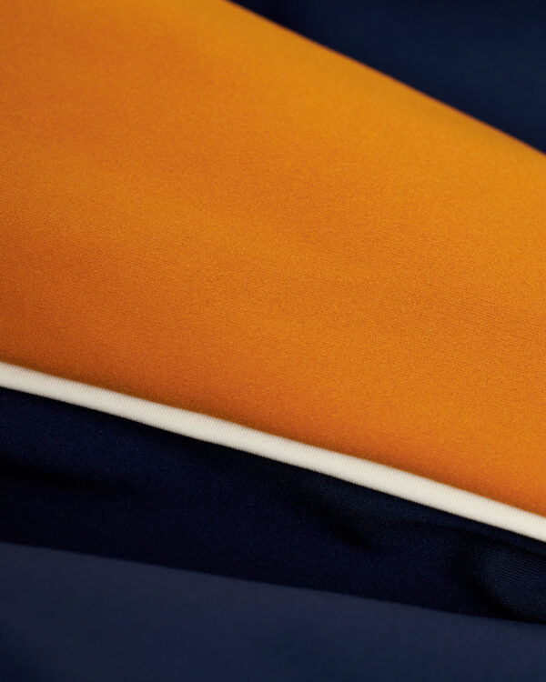 A close up of an European fit Dandy Del Mar Cassis Square Cut Swim Brief - Anchor in vibrant orange and blue fabric for leisure activities.
