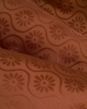 A close up of The Brisa Linen Blazer - Onyx by Dandy Del Mar, a brown fabric with a floral pattern showcasing fine linens.