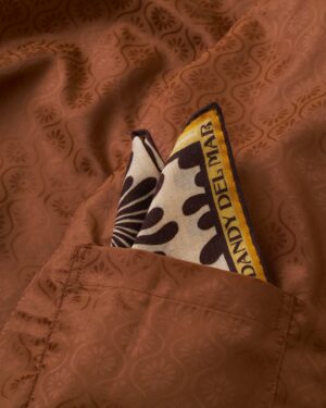 A Corsica Corduroy Jacket in Sangria, featuring a brown floral-patterned design, boasts a patterned pocket square with