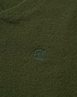 A close up of The Lima Sweater - Selva by Dandy Del Mar with a small logo on it.